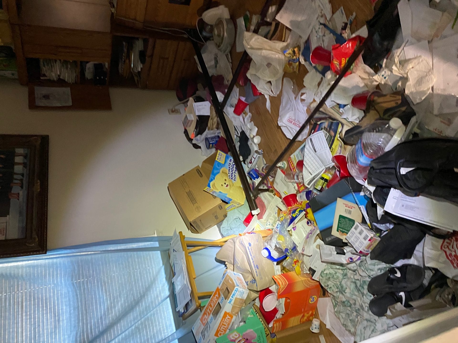 Image shows a bedroom blocked by trash and clutter. It's impossible to walk into the room. 