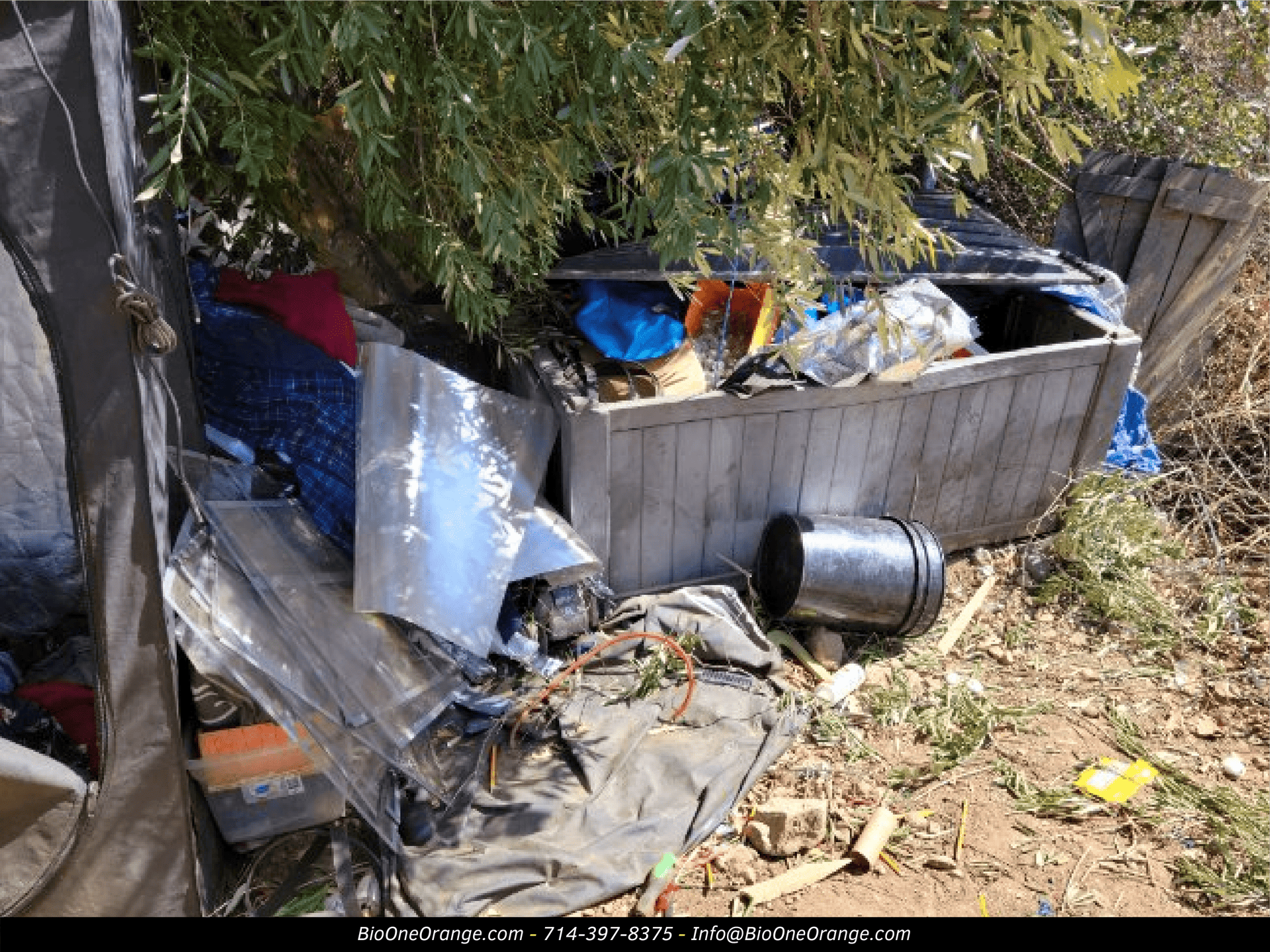 Image shows dumpster and debris found in encampment site near a residential neighborhood.